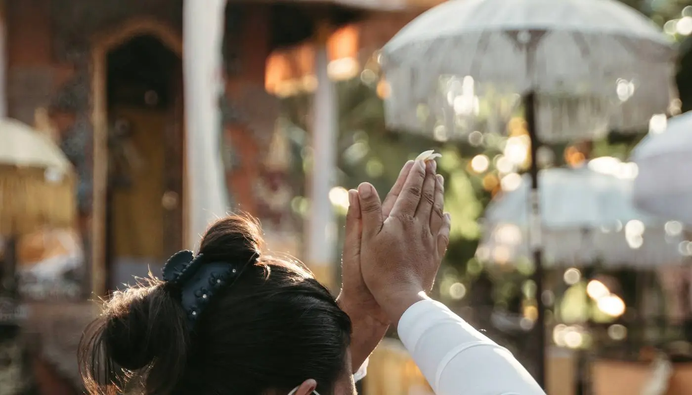 Woman in ceremonial dress praying at a Balinese temple